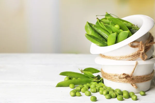 木のテーブルの上のボウルに新鮮な緑のエンドウ豆 — ストック写真