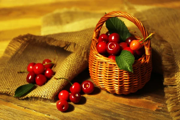 Γλυκά κεράσια σε ψάθινο καλάθι στο ξύλινο τραπέζι甜樱桃在木制的桌子上的柳条篮子里 — 图库照片