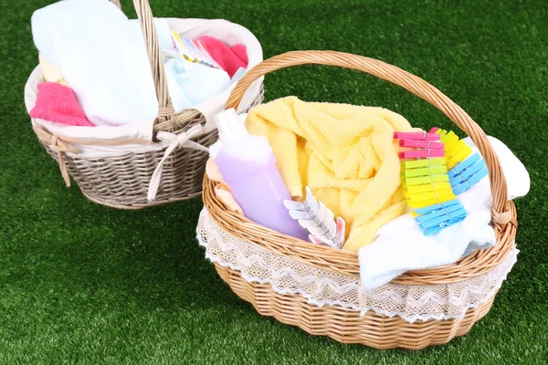 Colorful towels and clothes in baskets on green grass background — Stock Photo, Image