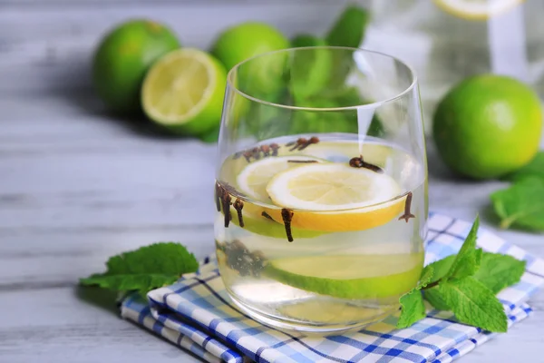 Свіжий літній напій з лаймом і гвоздиками в склі, на кольоровому дерев'яному фоні — стокове фото