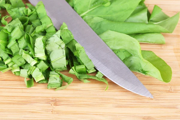 Chopped greens with knife on cutting board — Stock Photo, Image