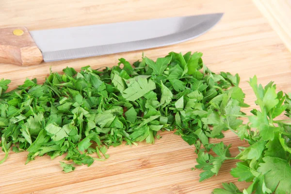 Chopped greens with knife on cutting board — Stock Photo, Image