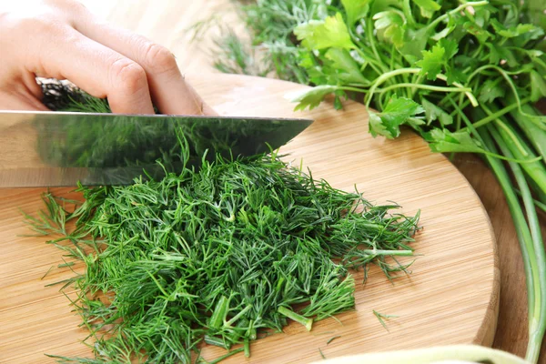 Female hand cutting greens on cutting board — Stock Photo, Image