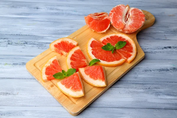 Ripe grapefruits on cutting board, on wooden table, on light background — Stock Photo, Image