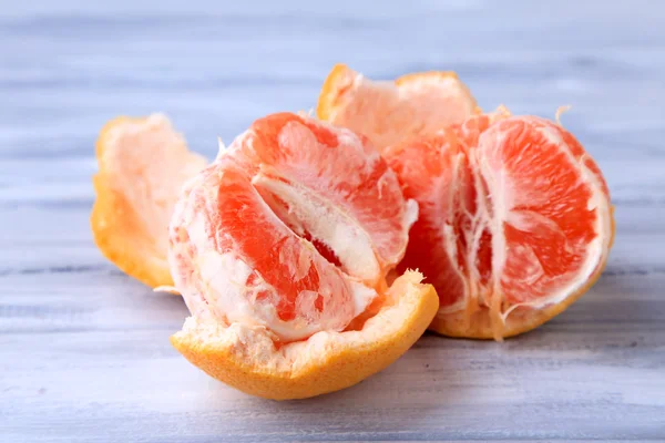 Ripe peeled grapefruits on color wooden background — Stock Photo, Image