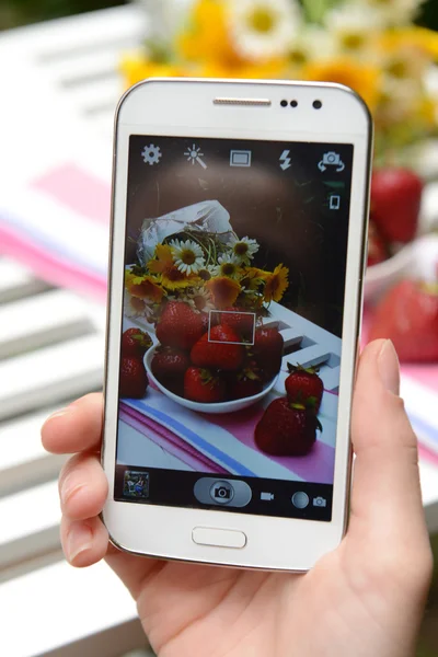Hand att göra foto av jordgubbar på mobiltelefon för sociala nätverk — Stockfoto