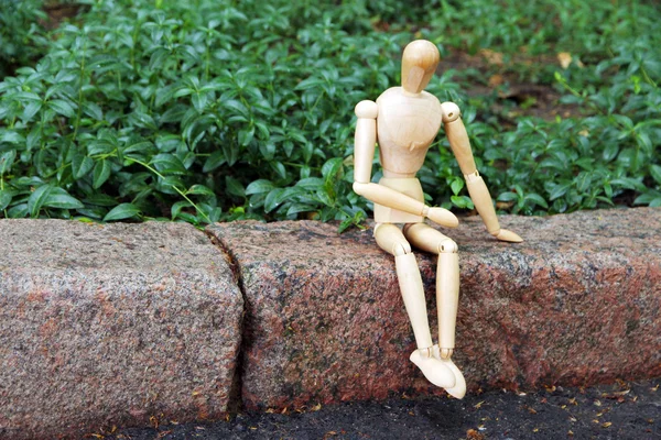 Marionnette pose en bois assise sur la pierre, à l'extérieur — Photo