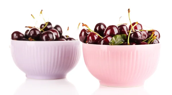 Сладкие вишни в цветных чашах изолированы на белом — стоковое фото