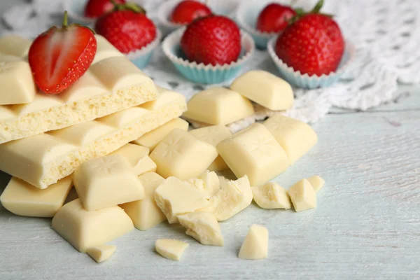 White chocolate bar with fresh strawberries, on color wooden background — Stock Photo, Image