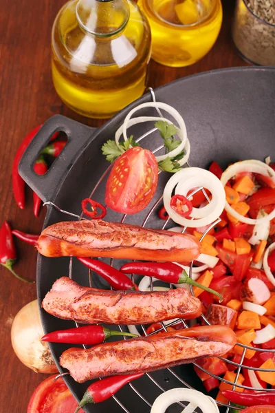Deliciosas salchichas con verduras en wok sobre mesa de madera de cerca —  Fotos de Stock
