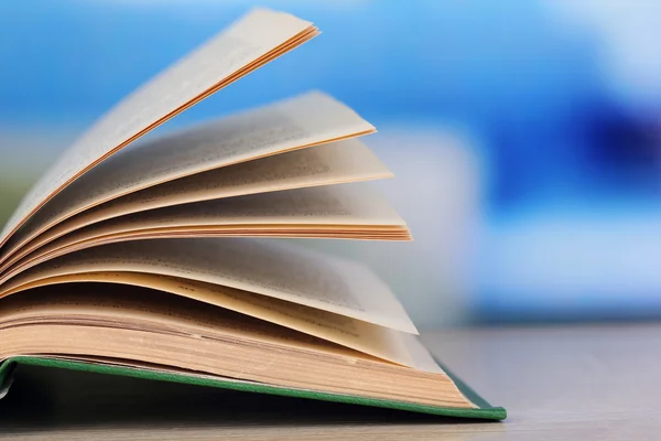 Livro aberto sobre mesa de madeira sobre fundo brilhante — Fotografia de Stock