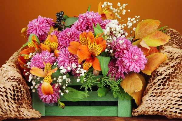 Kompozycja kwiaty w skrzyni na stole na brązowym tle — Zdjęcie stockowe