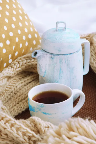 Tasse und Teekanne mit Schal auf dem Bett aus nächster Nähe — Stockfoto