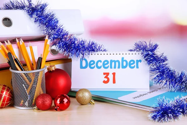 Table with office supplies, calendar and Christmas tinsel close-up — Stock Photo, Image