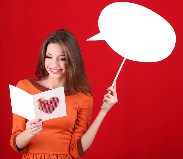 Mulher atraente com cartão postal, no fundo vermelho — Fotografia de Stock