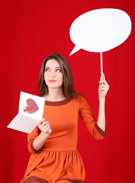 Привлекательная женщина с открыткой, на красном фоне — стоковое фото