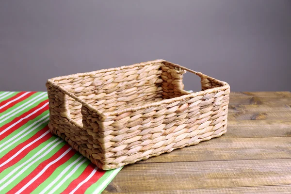 Cesta de vime vazia na mesa de madeira, no fundo escuro — Fotografia de Stock