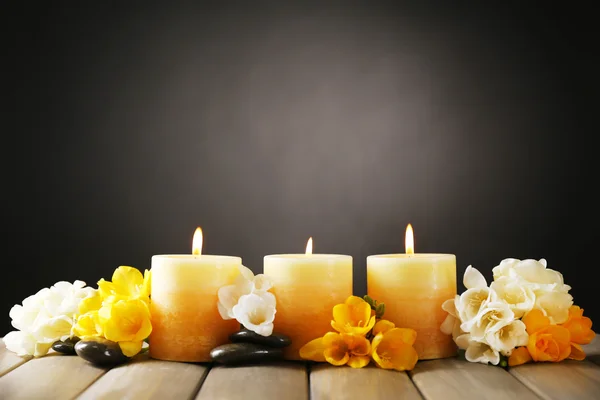 Schöne Kerzen mit Blumen auf Holzgrund — Stockfoto