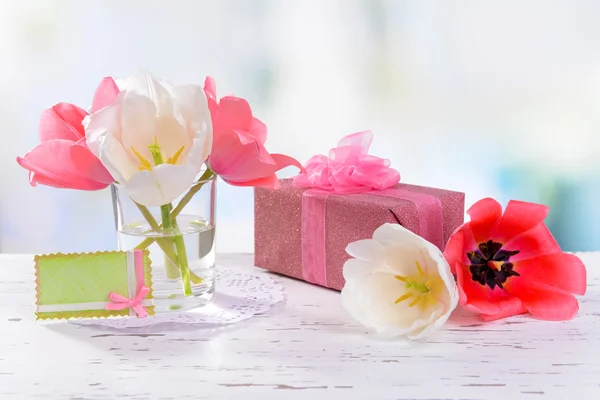 Piękne tulipany w wiaderku w wazonie na stole na jasnym tle — Zdjęcie stockowe