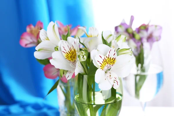 Freesias in glasses on table on fabric background — Stock Photo, Image