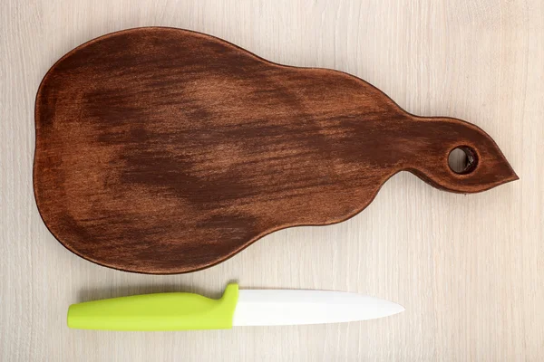 Kitchen knife and cutting board on wooden table — Stock Photo, Image