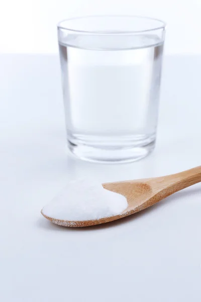 Spoon of baking soda over glass of water, isolated on white — Stock Photo, Image