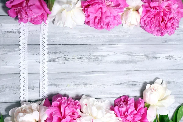 Розовые и белые пионы на цветном деревянном фоне — стоковое фото