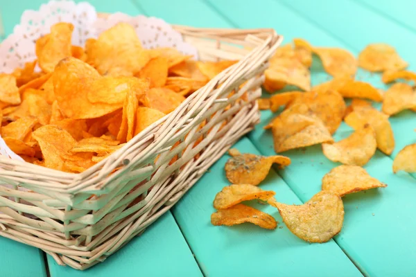 Hausgemachte Kartoffelchips auf farbigem Holztisch — Stockfoto