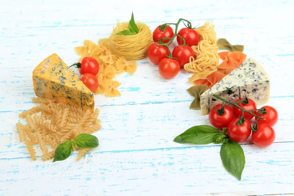 Massas, queijos e tomates diferentes em close-up de mesa de madeira — Fotografia de Stock