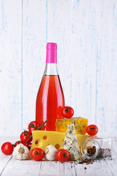 Pink wine and different kinds of cheese on wooden background — Stock Photo, Image