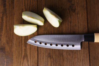 Mutfak bıçağı ve yeşil elma, ahşap arka planda.