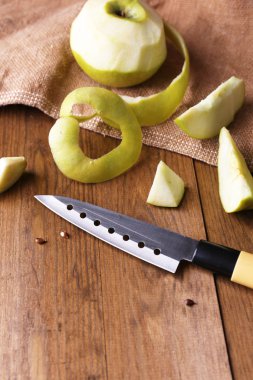 Mutfak bıçağı ve yeşil elma, ahşap arka planda.