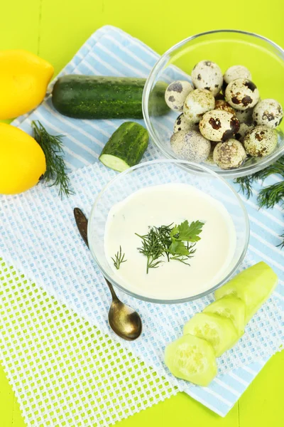 Yogur de pepino en un tazón de vidrio, en una servilleta de color, sobre un fondo de madera — Foto de Stock