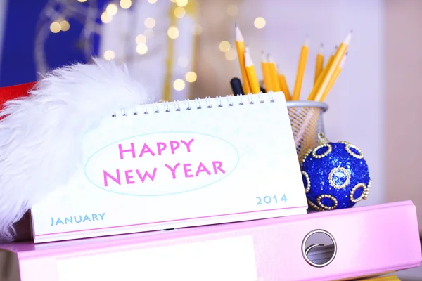 Mesa con suministros de oficina, calendario y oropel de Navidad de cerca —  Fotos de Stock