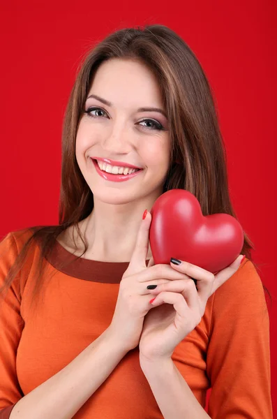Mulher atraente com coração, no fundo vermelho — Fotografia de Stock