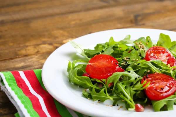 Ensalada verde elaborada con rúcula, tomate y sésamo sobre plato, sobre fondo de madera — Foto de Stock