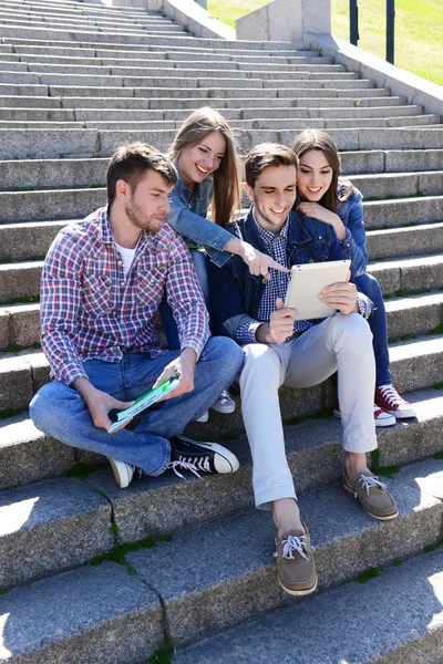 Estudantes felizes sentados nas escadas do parque — Fotografia de Stock