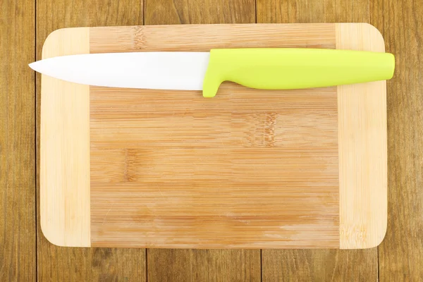 Kitchen knife and cutting board on wooden table — Stock Photo, Image