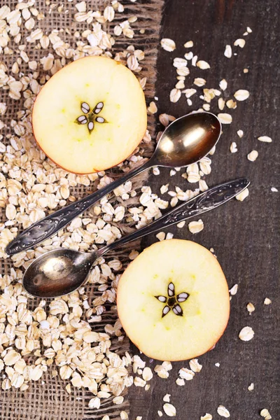 苹果用燕麦片和复古勺子上麻布，彩色木背景 — 图库照片