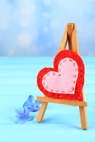 Hermoso corazón pequeño caballete decorativo sobre fondo azul — Foto de Stock