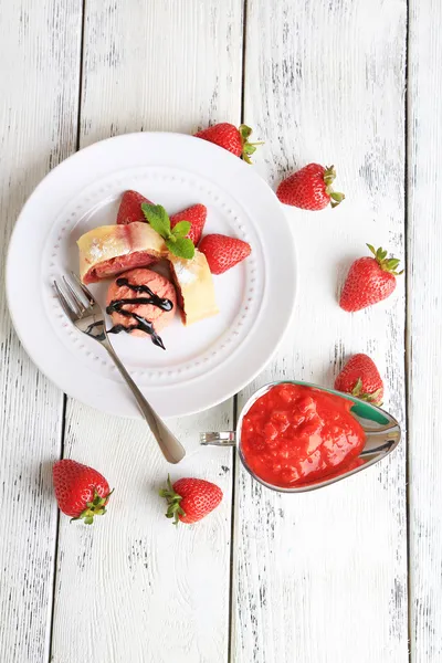 Sabroso strudel casero con helado, fresa fresca y hojas de menta en el plato, sobre fondo de madera — Foto de Stock