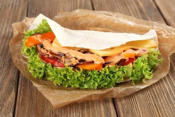 Veggie wrap filled with chicken and fresh vegetables on wooden table, close up — Stock Photo, Image