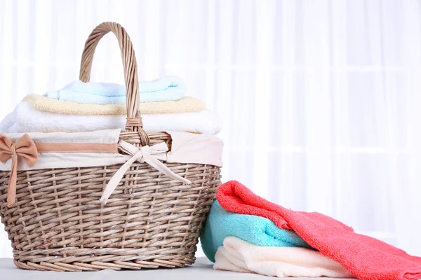Kleurrijke handdoeken in mand op lichte achtergrond — Stockfoto
