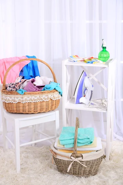 Asciugamani e vestiti colorati in cestini sul tavolo, su sfondo interno — Foto Stock