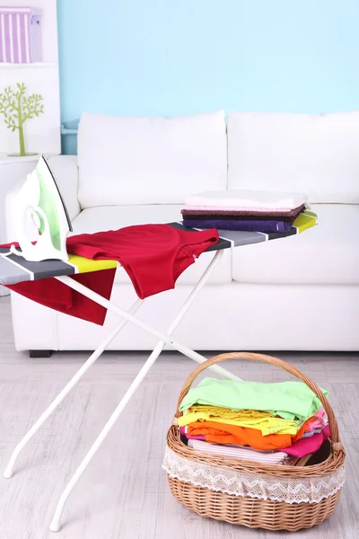 Basket with laundry and ironing board on home interior background — Stock Photo, Image