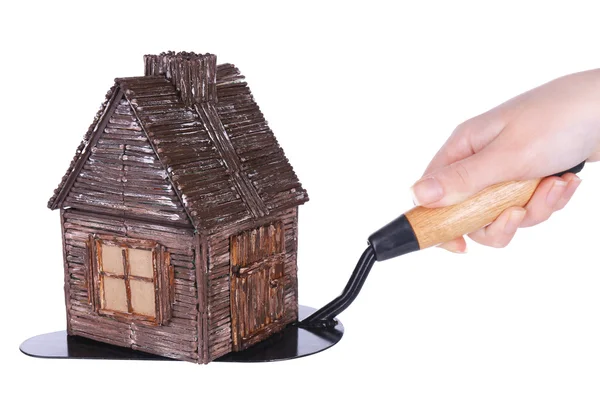 Mão segurando casa de brinquedo de madeira na espátula, isolado no branco — Fotografia de Stock