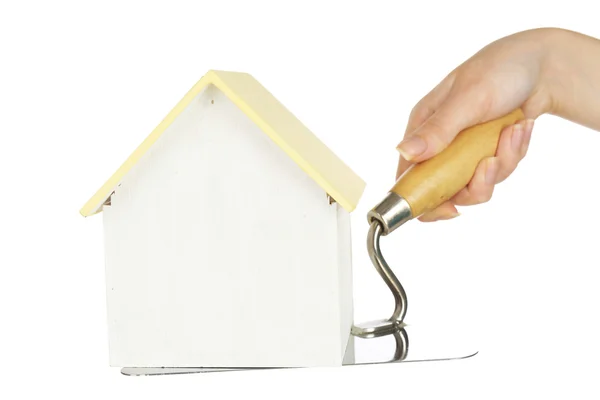 Hand holding wooden toy house on trowel, isolated on white — Stock Photo, Image