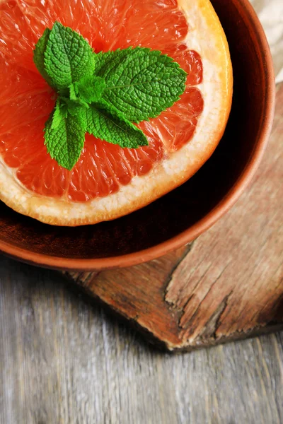 Del av mogen grapefrukt i skål, på trä bakgrund — Stockfoto