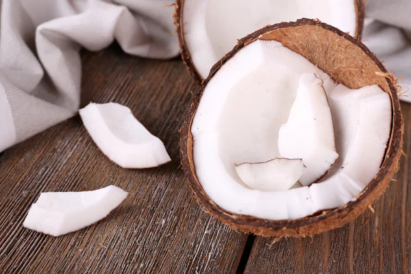 Gebroken kokosnoot met servet op houten achtergrond — Stockfoto
