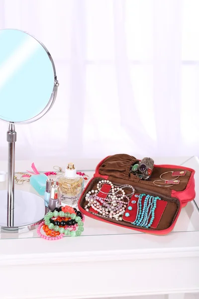 Handtas met accessorises en parfums in flessen op tafel op huis interieur achtergrond — Stockfoto